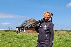 Vogelwartin mit Fernrohr am Deich